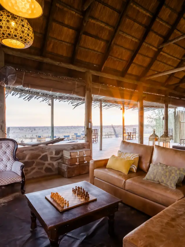 Luxury lounge with leather seating overlooking vast savanna landscape at dusk, Daka Plains Camp, Hwange National Park, Zimbabwe