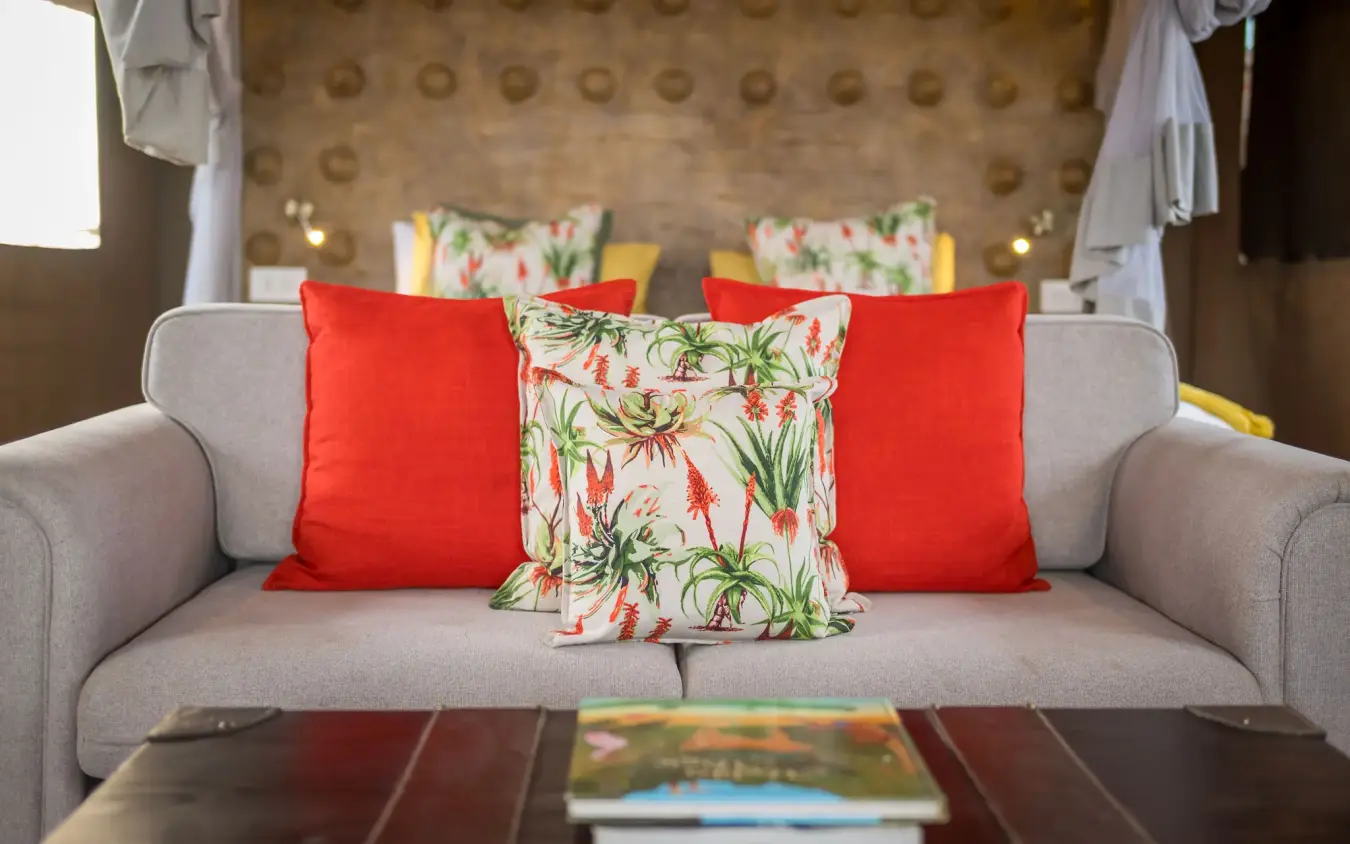 Luxury suite interior with tropical patterned cushions on gray sofa, Daka Plains Camp, Hwange National Park, Zimbabwe