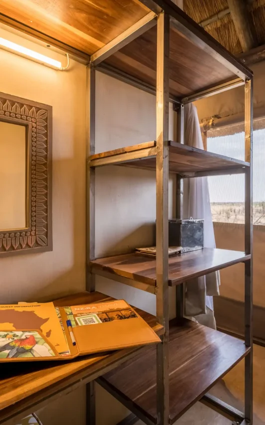 Modern lodge bedroom with wooden shelving and valley views through windows, Daka Plains Camp, Hwange National Park, Zimbabwe