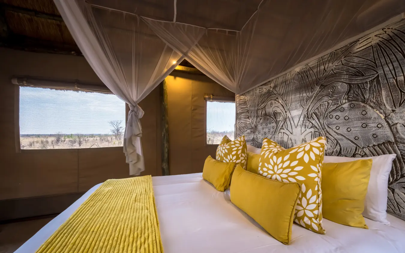 Luxury safari bedroom with yellow accents and expansive landscape views, Daka Plains Camp, Hwange National Park, Zimbabwe