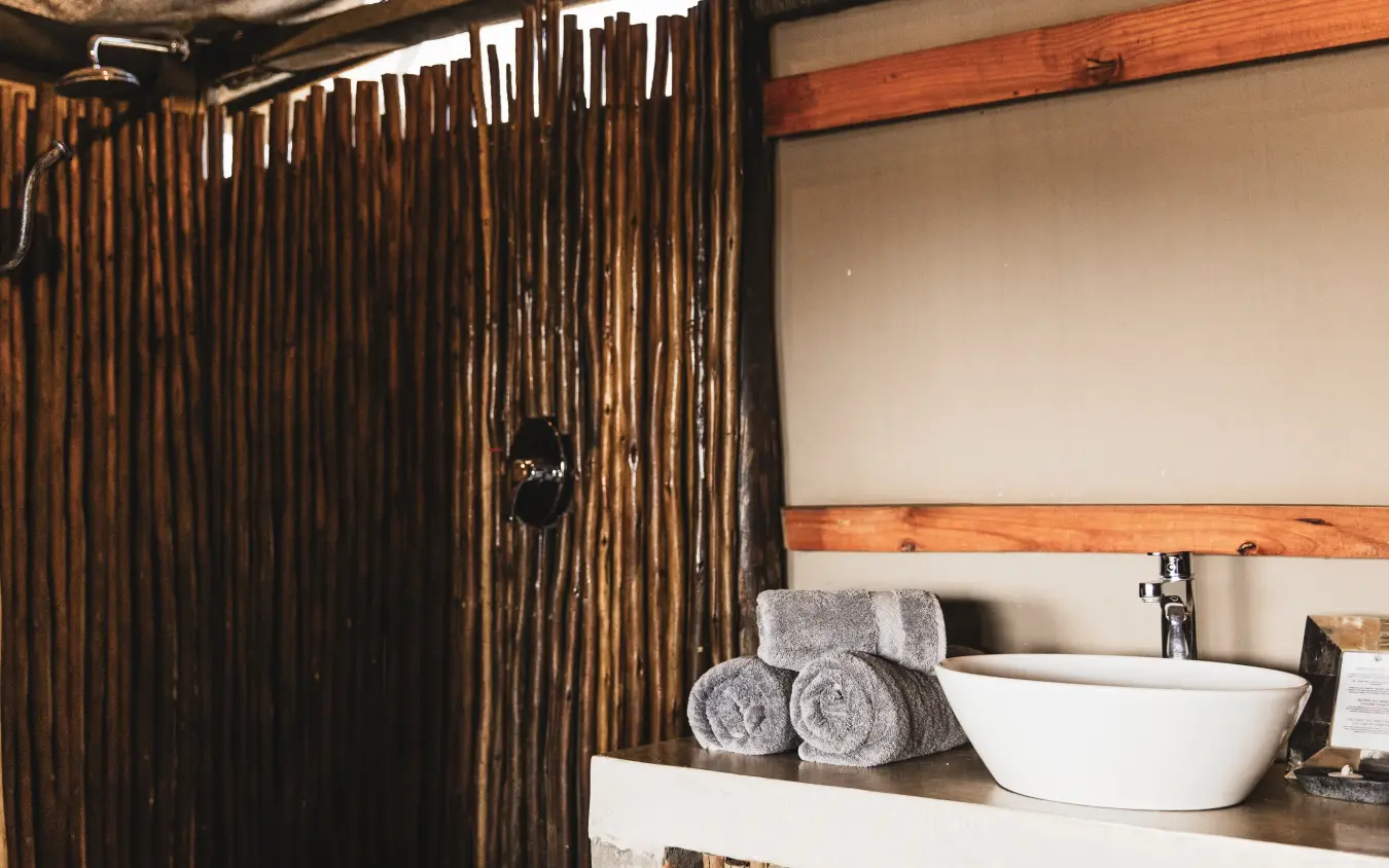 Rustic bathroom with wooden partition shower and freestanding basin sink, Davison’s Camp, Hwange National Park, Zimbabwe
