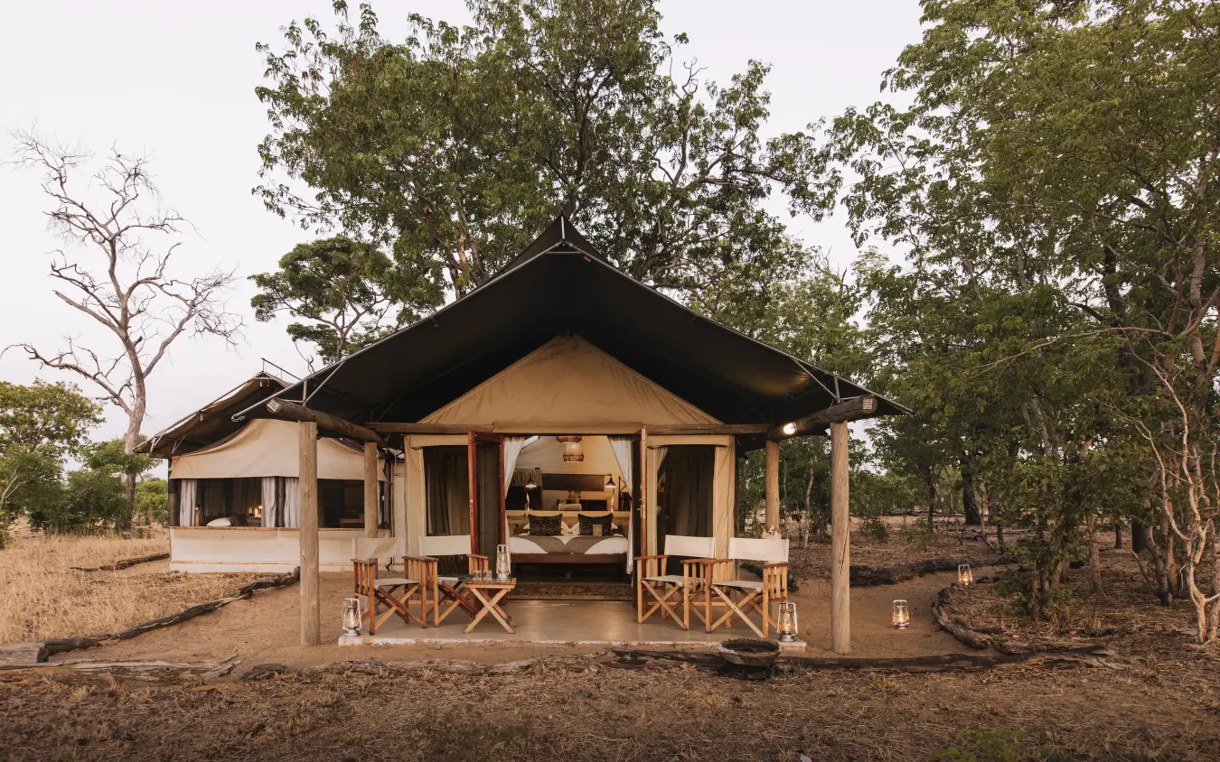 Luxury safari tent with wooden deck and chairs in woodland setting, Davison’s Camp, Hwange National Park, Zimbabwe