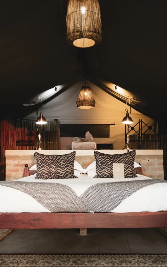 Luxury safari tent bedroom with peaked canvas ceiling and decorative pendant lighting, Davison’s Camp, Hwange National Park, Zimbabwe