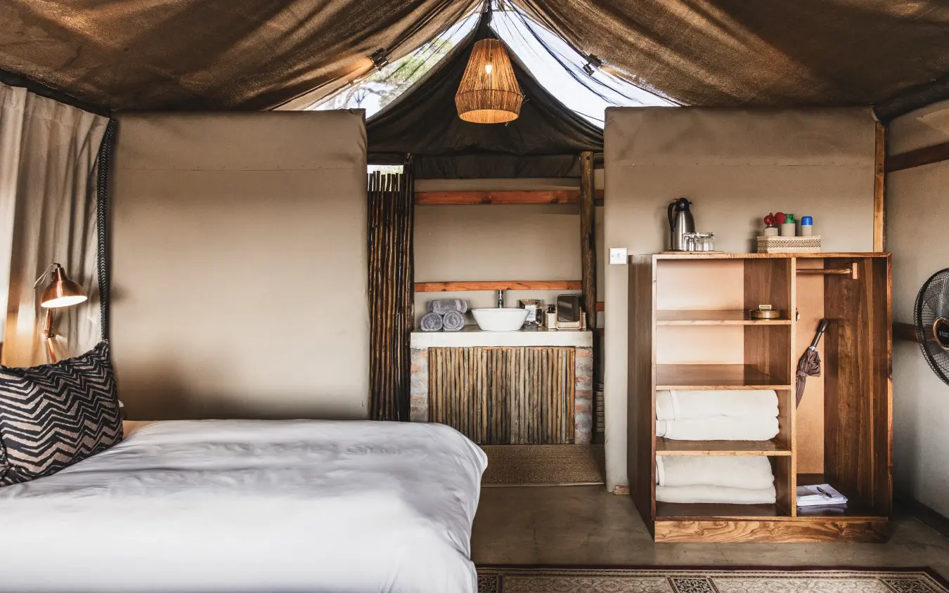 Luxury safari tent interior with canopy bed and wooden furnishings, Davison’s Camp, Hwange National Park, Zimbabwe