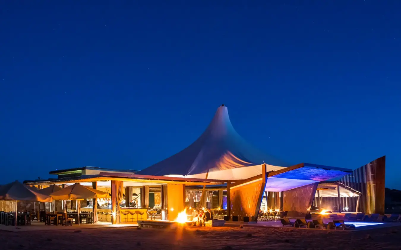 Illuminated tent-style lodge structures at dusk in desert, Dead Valley Lodge, Sossusvlei, Namibia