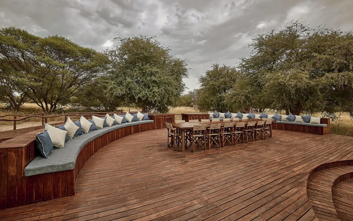 Wooden deck with curved seating and dining area overlooking savanna, Deception Valley Lodge, Central Kalahari, Botswana