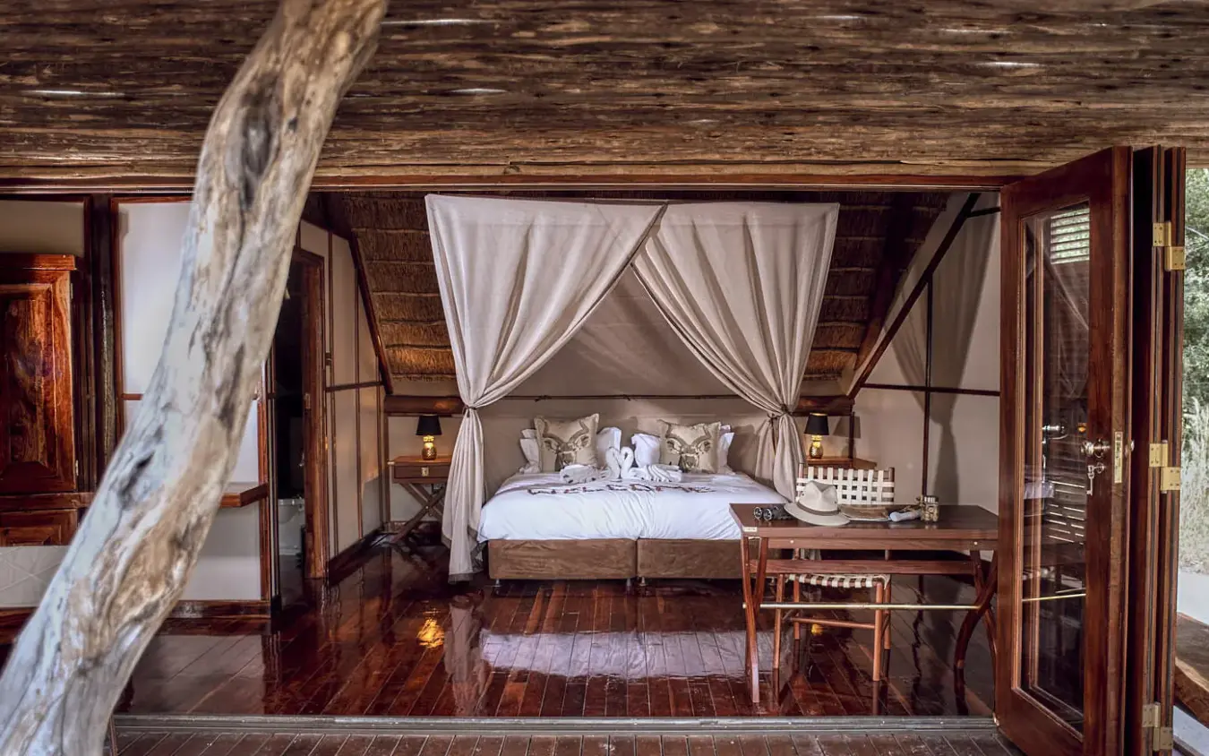 Bedroom with canopy bed and open deck overlooking savanna, Deception Valley Lodge, Central Kalahari, Botswana