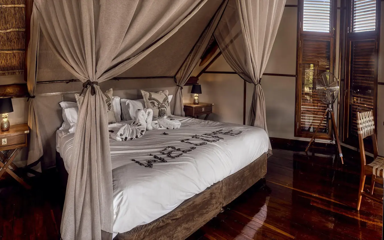Luxury canopy bed with draped curtains and wooden furnishings, Deception Valley Lodge, Central Kalahari, Botswana