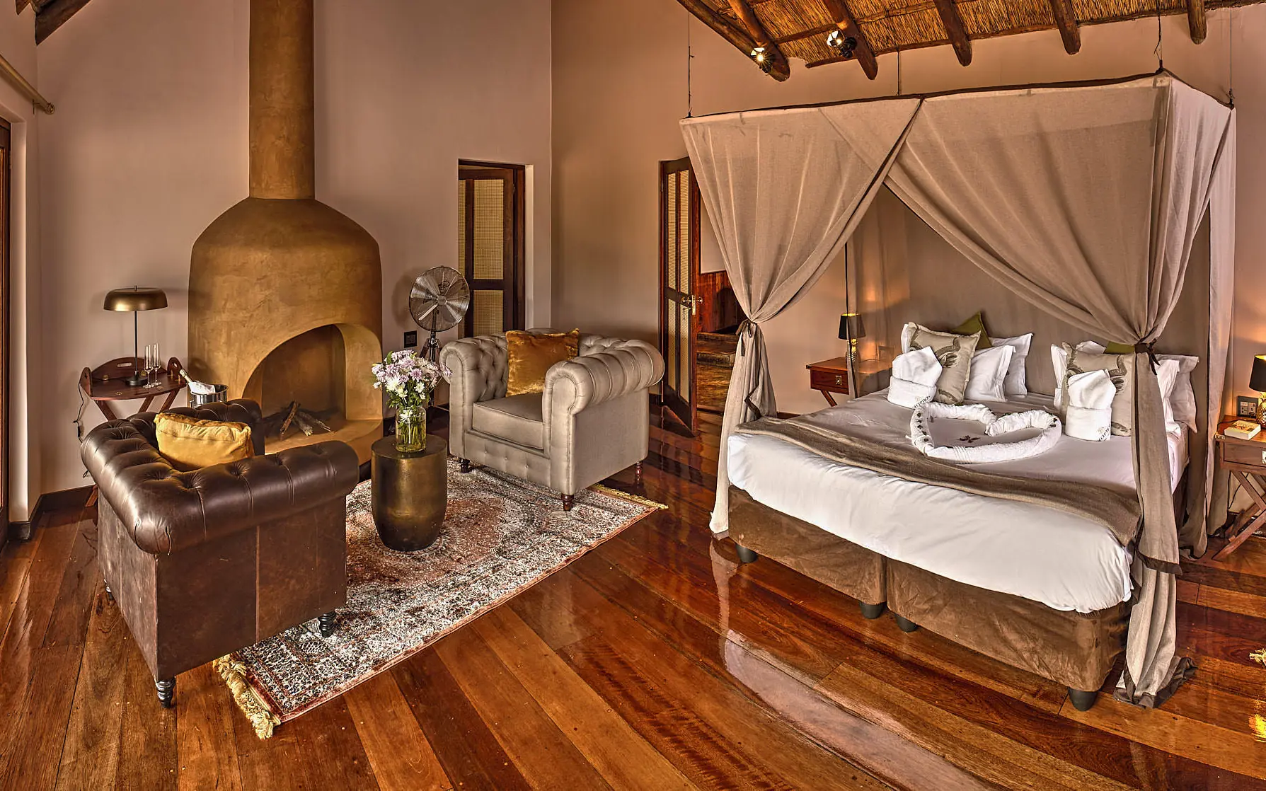 Spacious bedroom with four-poster bed and fireplace, Deception Valley Lodge, Central Kalahari, Botswana