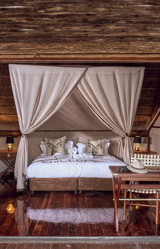 Bedroom with canopy bed and open deck overlooking savanna, Deception Valley Lodge, Central Kalahari, Botswana