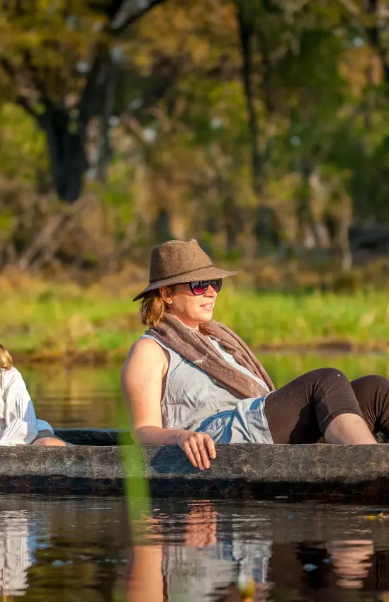 Adult and child in traditional dugout canoe on waterway, Delta Camp, The Okavango Delta, Botswana