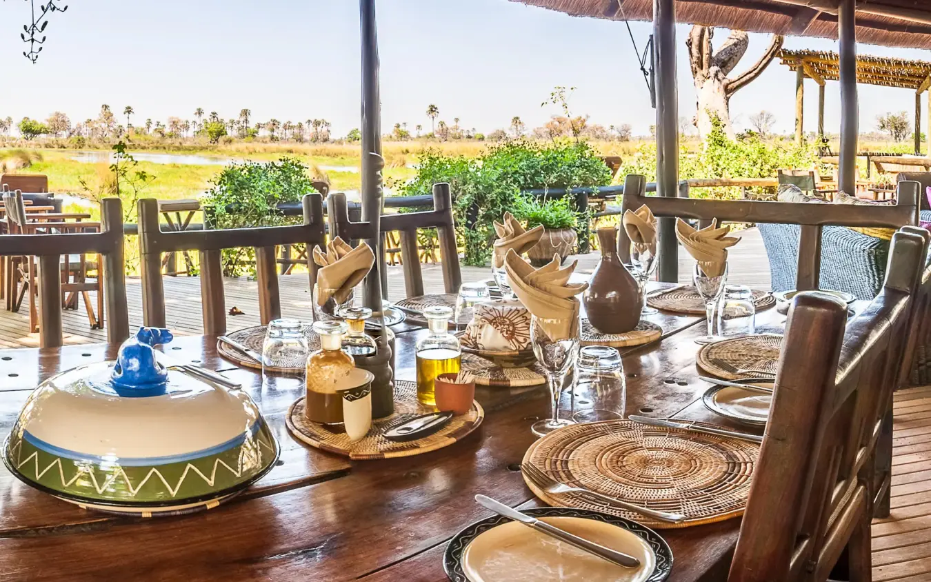 Wooden deck dining area overlooking delta waterway and landscape, Delta Camp, The Okavango Delta, Botswana