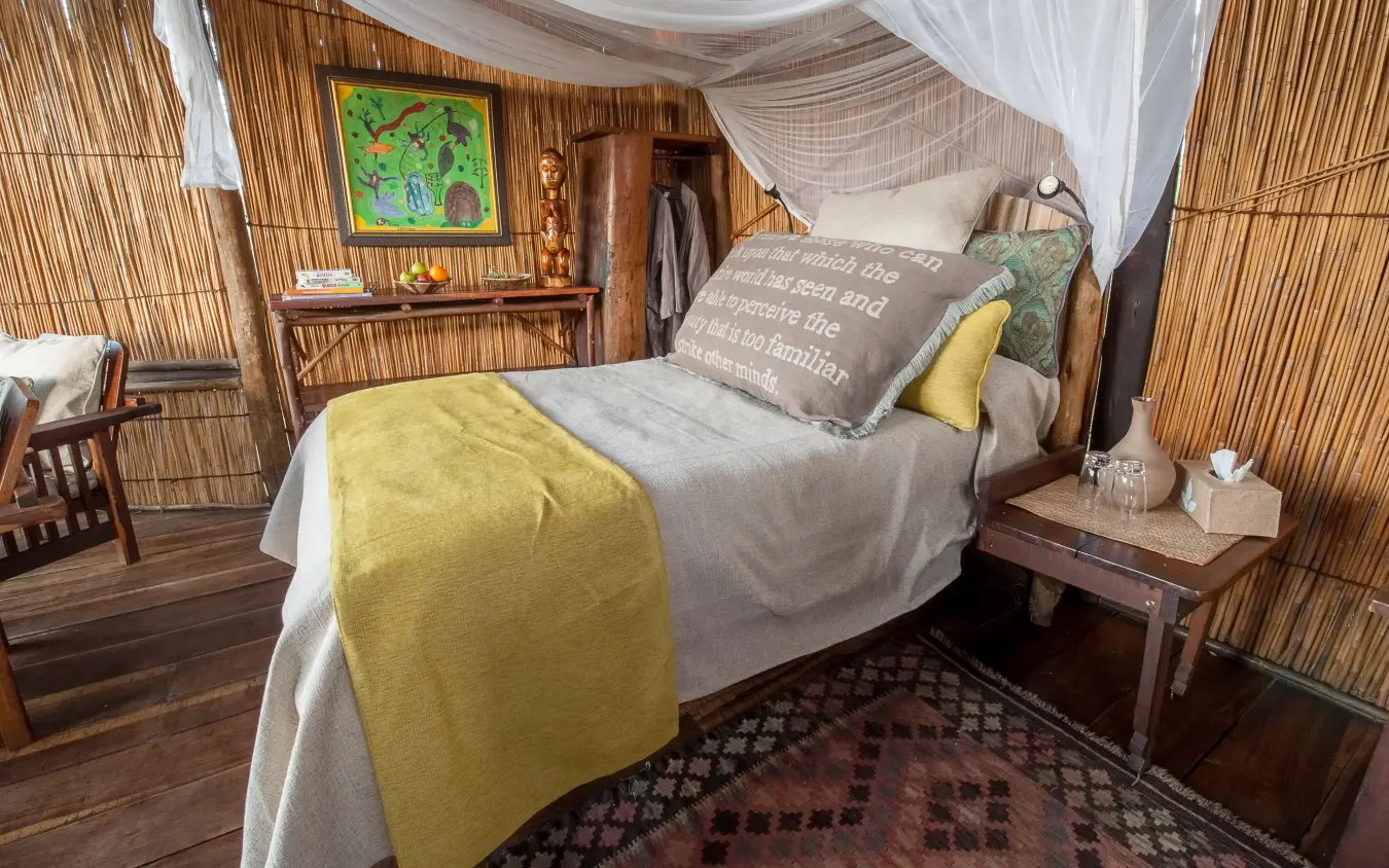 Bedroom with wooden frame bed and mosquito netting, Delta Camp, The Okavango Delta, Botswana