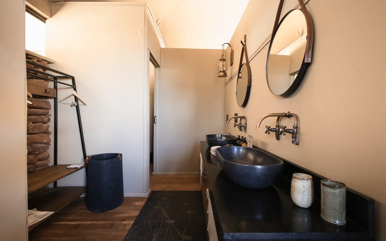 Luxury bathroom with navy basin sink and round mirrors in safari lodge, Desert Rhino Camp, Damaraland, Namibia