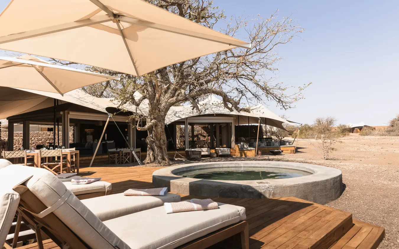Luxury safari lodge with sunken fire pit and acacia tree at dusk, Desert Rhino Camp, Damaraland, Namibia