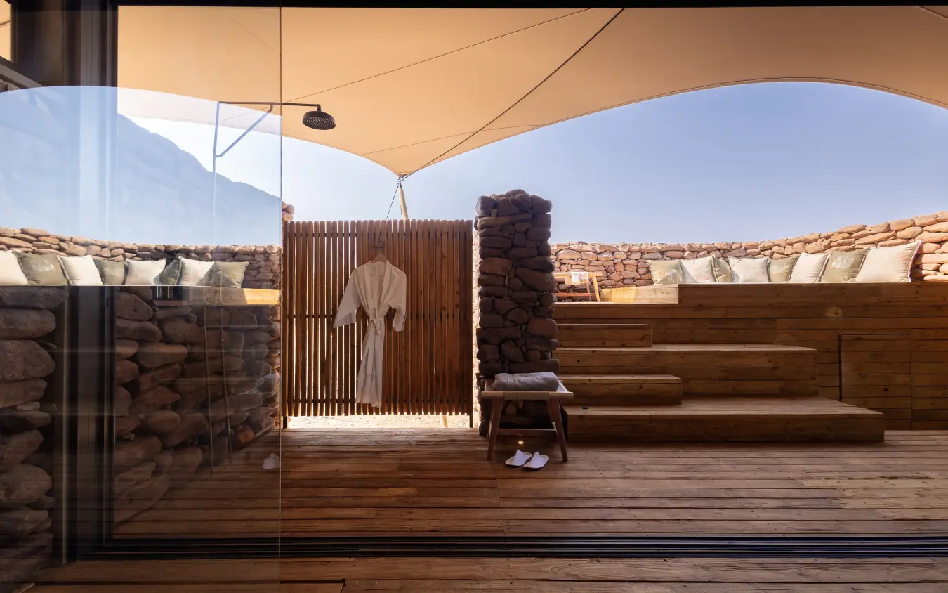 Luxury safari lodge deck with stone walls and savanna views at dusk, Desert Rhino Camp, Damaraland, Namibia