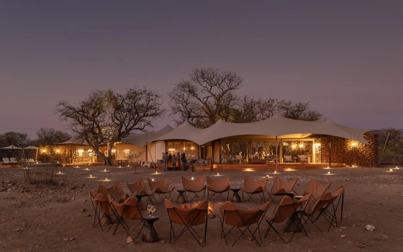 Luxury safari camp with canvas tents and firelit seating area at dusk, Desert Rhino Camp, Damaraland, Namibia
