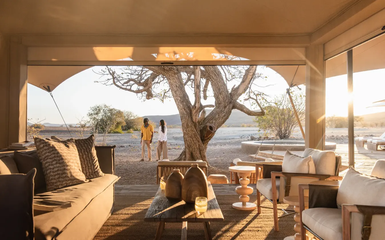 Luxury lounge pavilion overlooking river with guests and large acacia tree, Desert Rhino Camp, Damaraland, Namibia