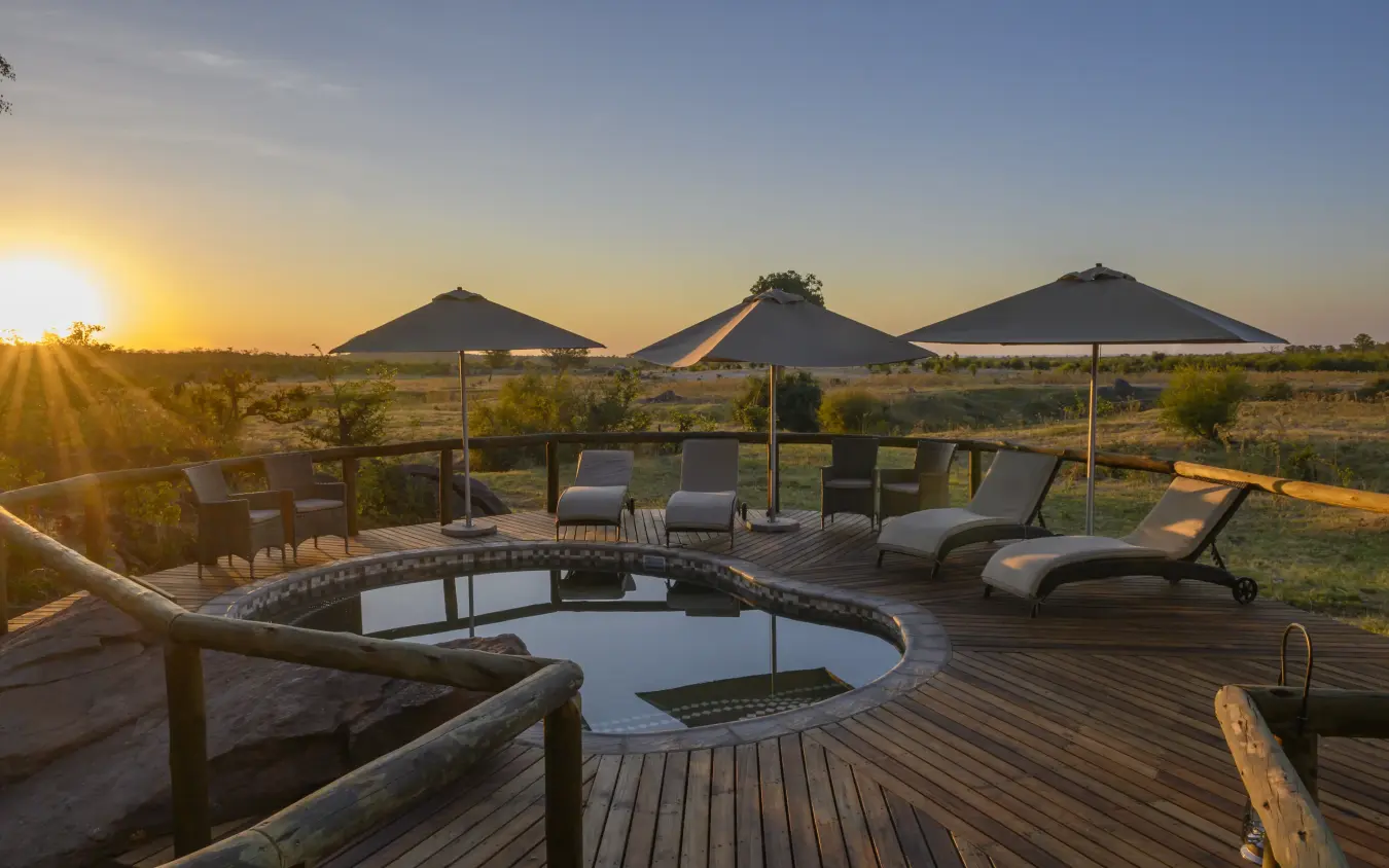 Wooden deck with plunge pool and loungers overlooking savanna at sunset, Deteema Springs Camp, Hwange National Park, Zimbabwe