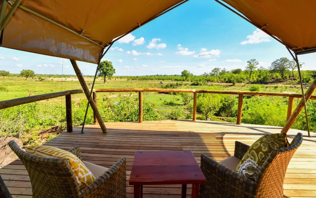Luxury safari lodge platform with woven chairs overlooking vast grassland savanna, Deteema Springs Camp, Hwange National Park, Zimbabwe