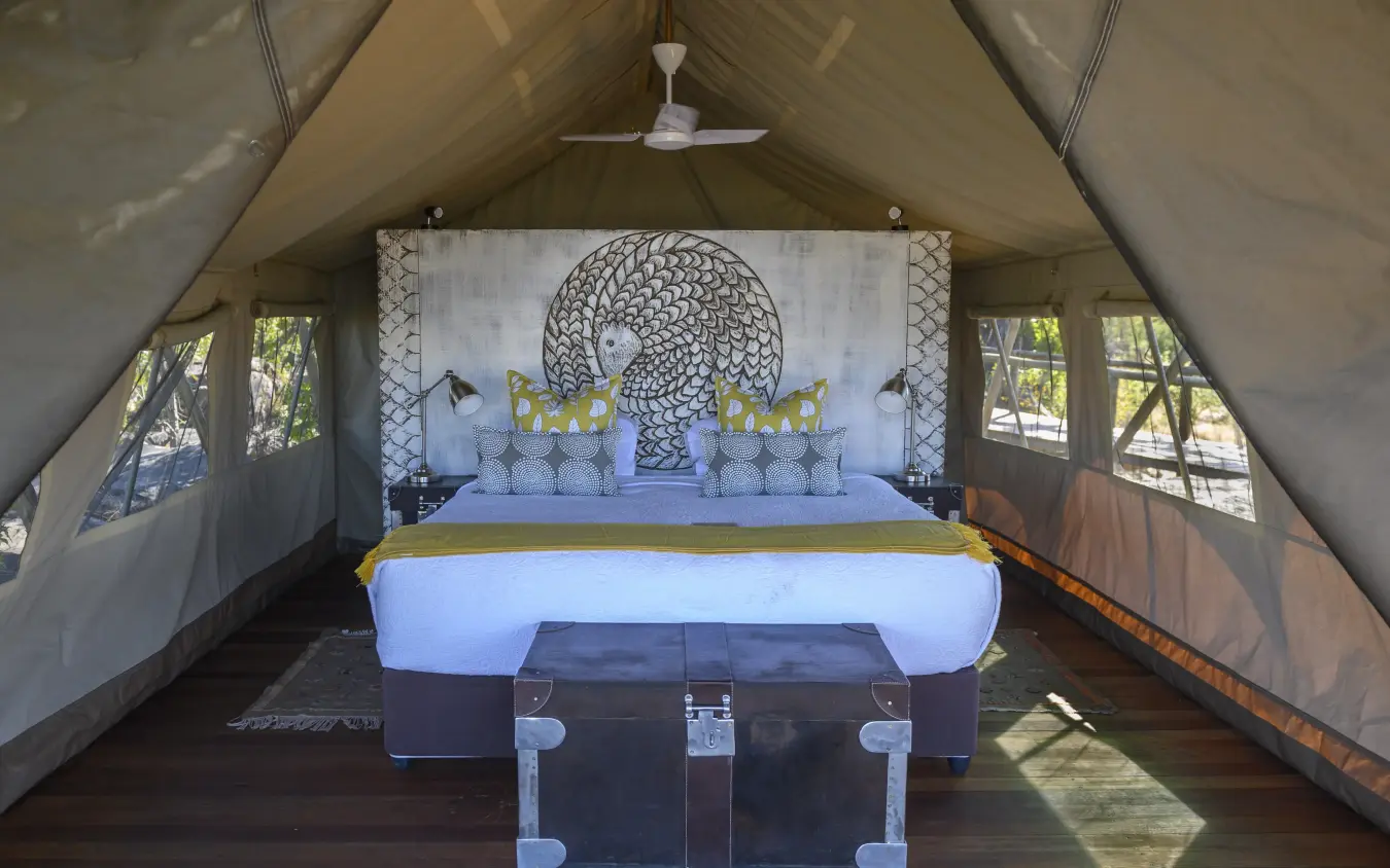 Glamping tent interior with blue bed and decorative headboard artwork, Deteema Springs Camp, Hwange National Park, Zimbabwe