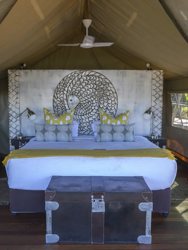 Glamping tent interior with blue bed and decorative headboard artwork, Deteema Springs Camp, Hwange National Park, Zimbabwe