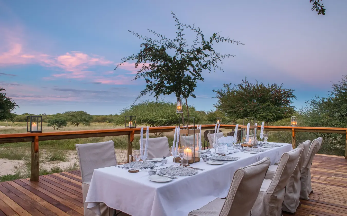 Outdoor dining setup on wooden deck at sunset, Dinaka, Central Kalahari, Botswana
