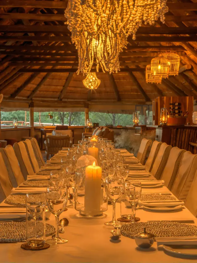 Long dining table set for evening service under wooden beams, Dinaka, Central Kalahari, Botswana