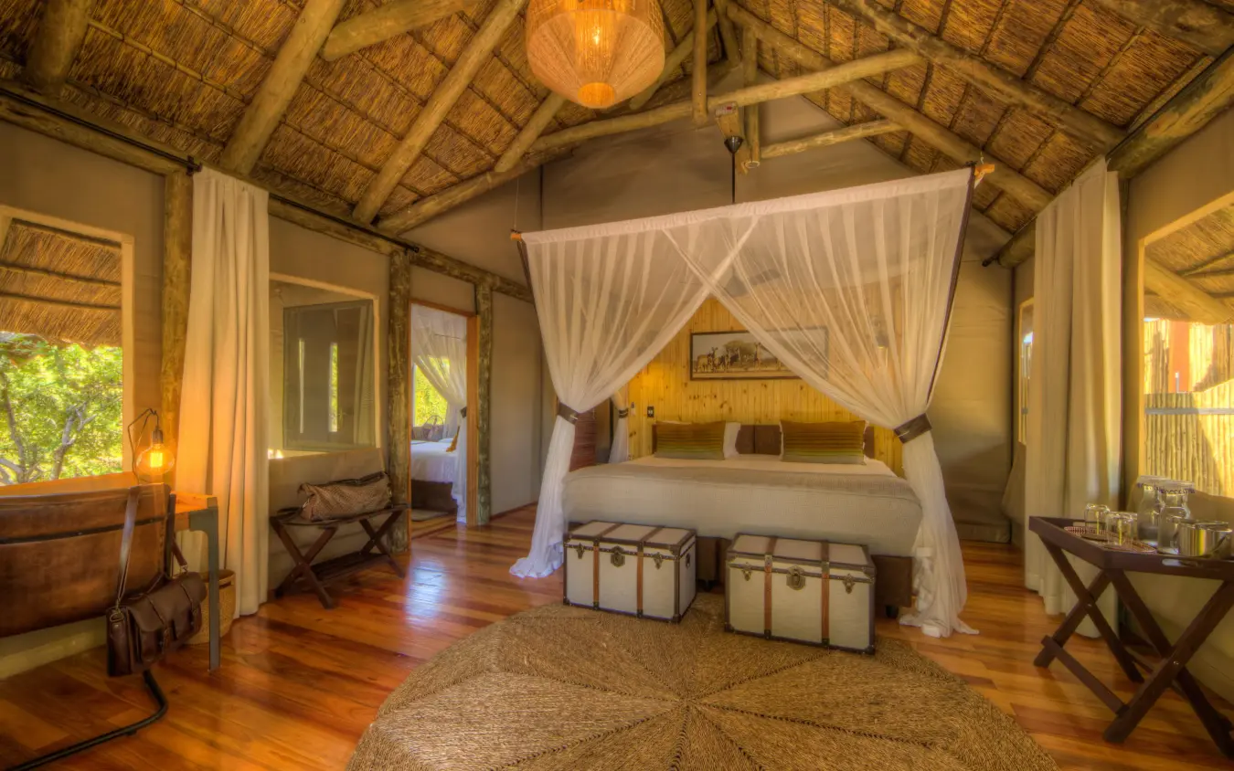 Spacious bedroom suite with four-poster canopy bed and wooden furnishings, Dinaka, Central Kalahari, Botswana