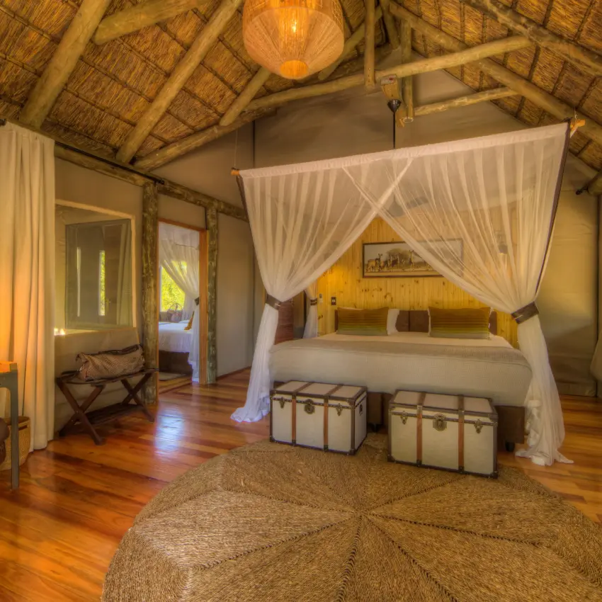 Spacious bedroom suite with four-poster canopy bed and wooden furnishings, Dinaka, Central Kalahari, Botswana