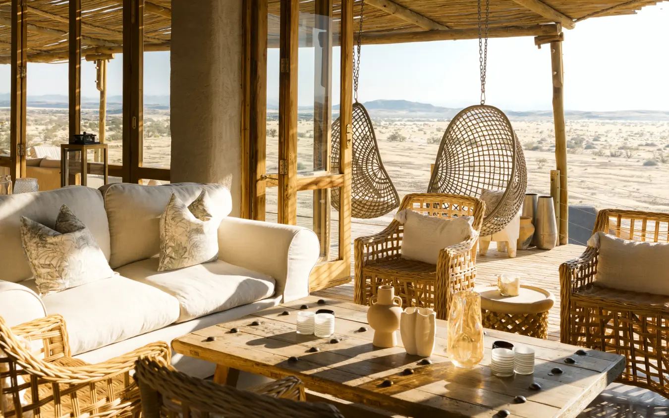 Open-air lounge with hanging chairs overlooking vast savanna landscape, Doro Nawas Camp, Damaraland, Namibia
