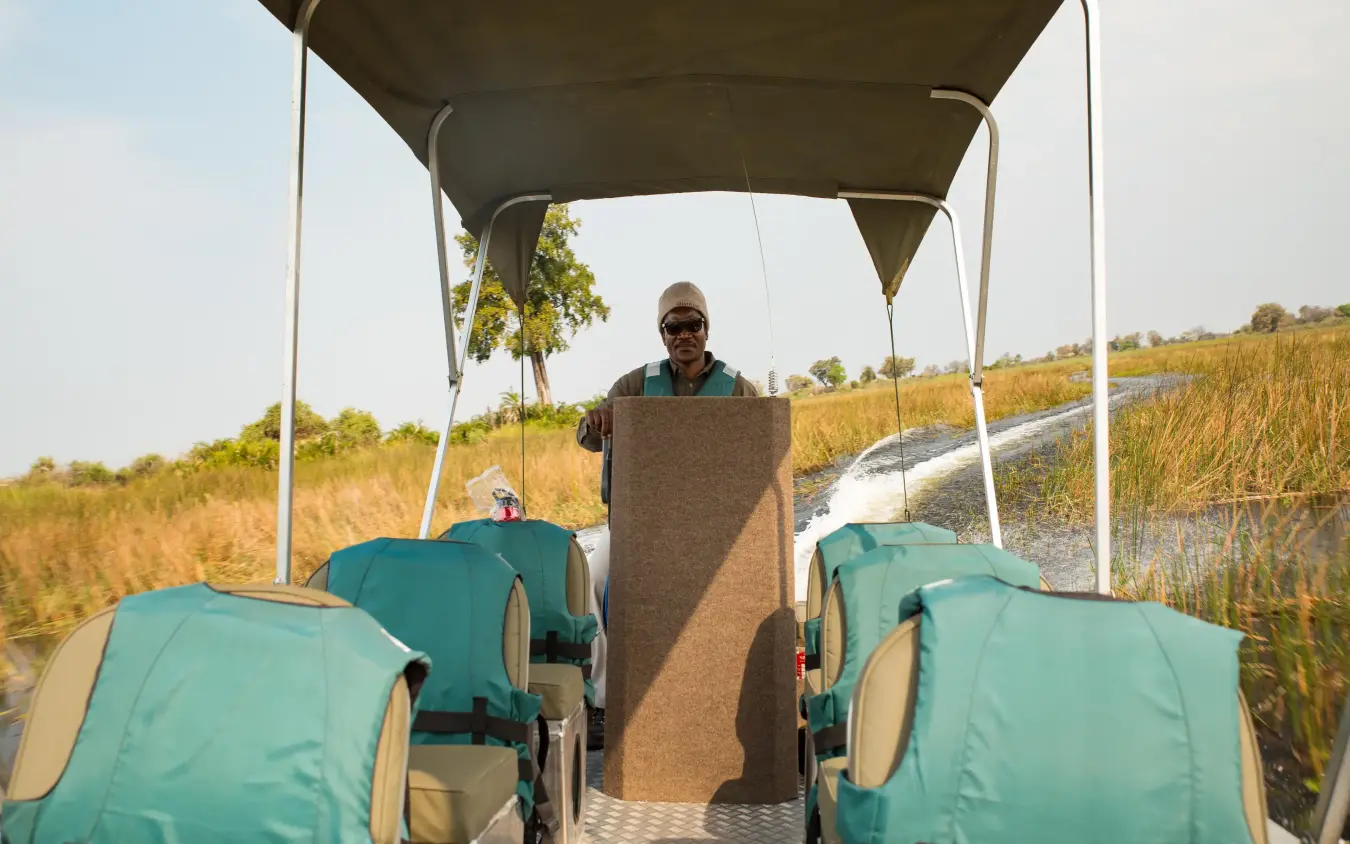 Guide standing in open safari vehicle with teal seats, Duba Explorers Camp, The Okavango Delta, Botswana