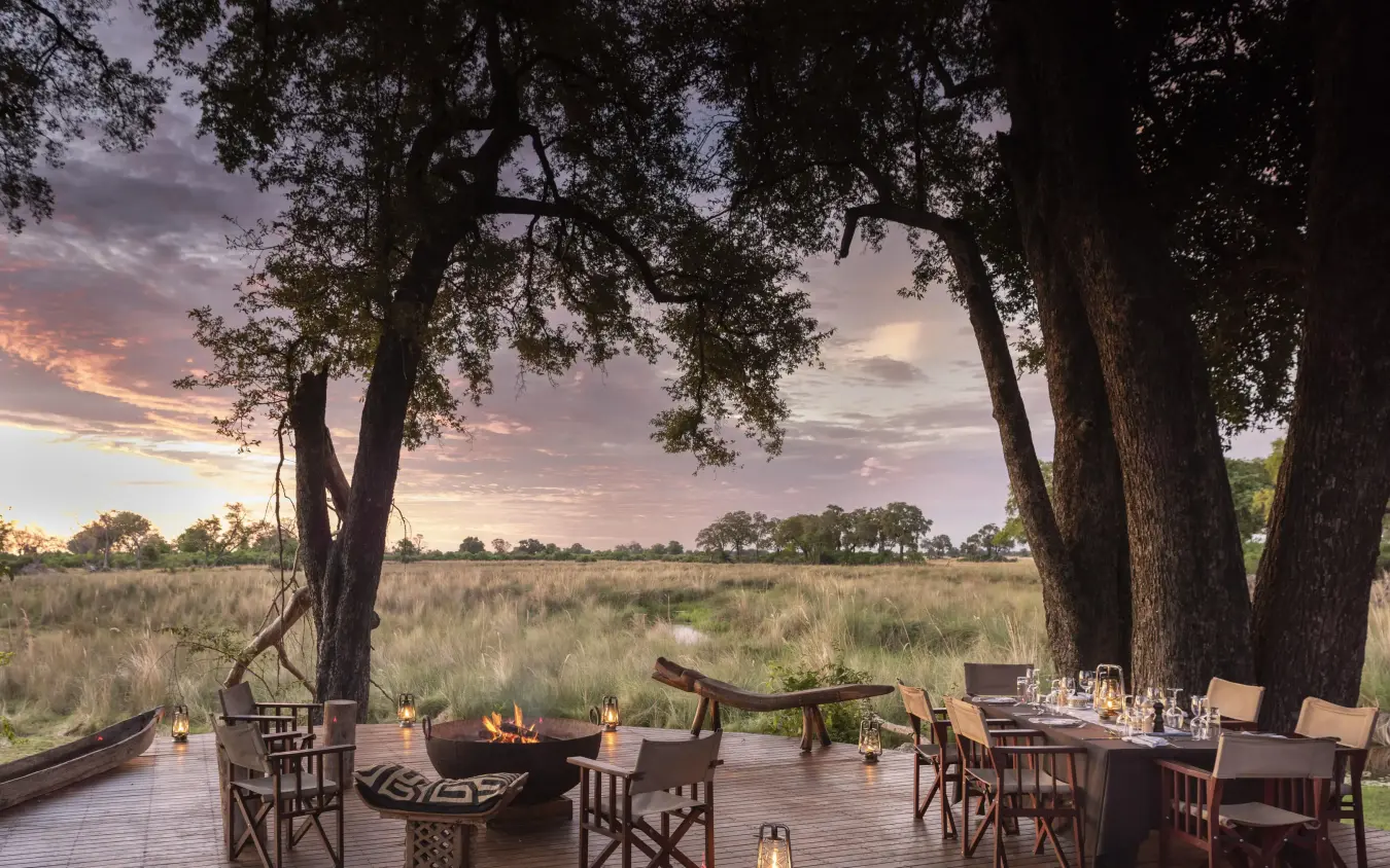 Wooden deck with fire pit overlooking savanna at sunset, Duba Explorers Camp, The Okavango Delta, Botswana