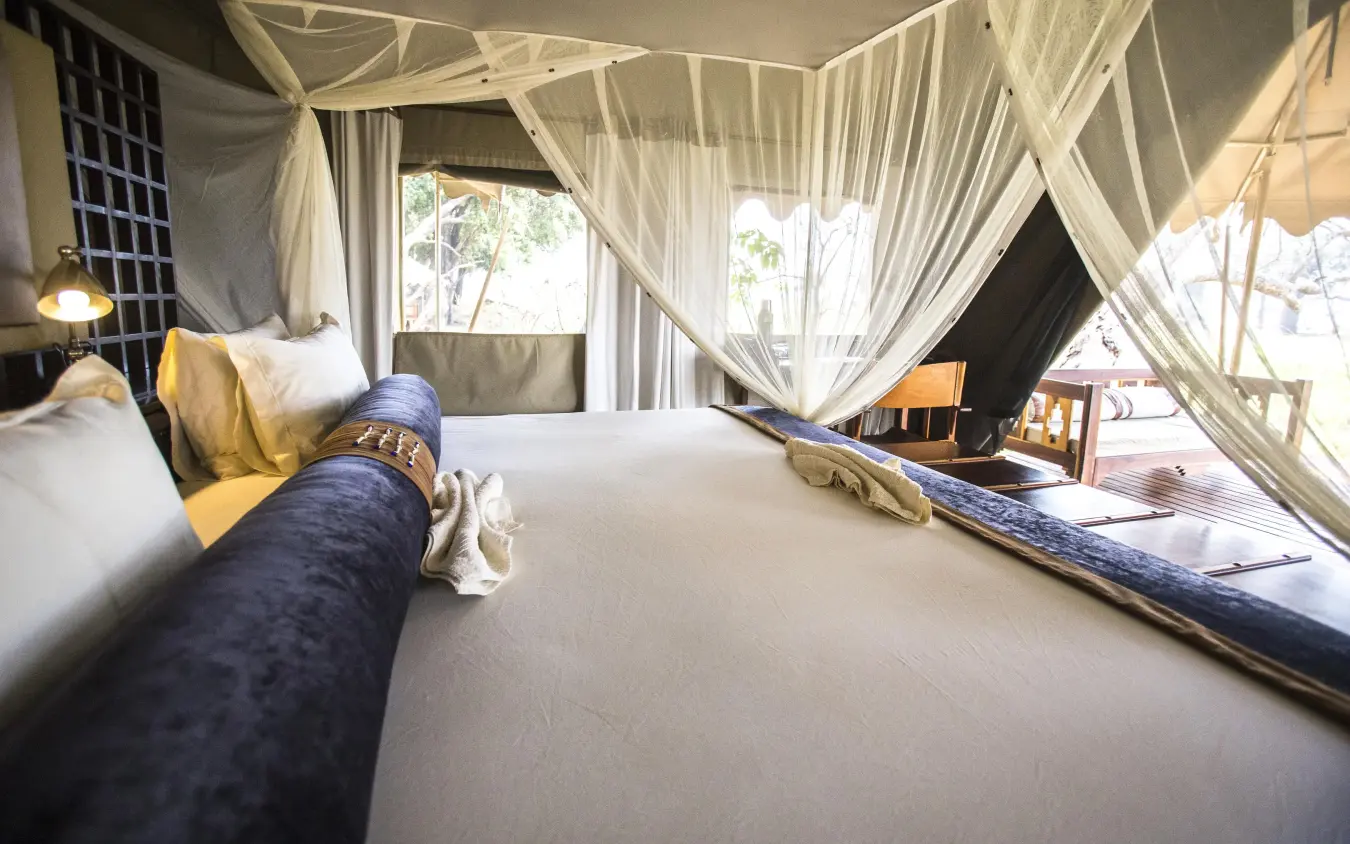 Luxury tent bedroom with flowing white drapes and deck access, Duba Explorers Camp, The Okavango Delta, Botswana