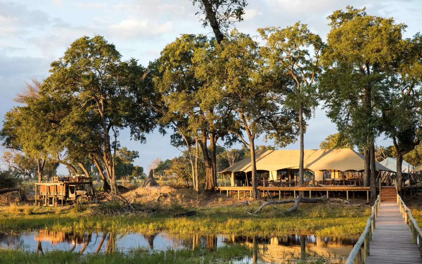 Safari lodge with canvas tents beside water and trees, Duba Explorers Camp, The Okavango Delta, Botswana