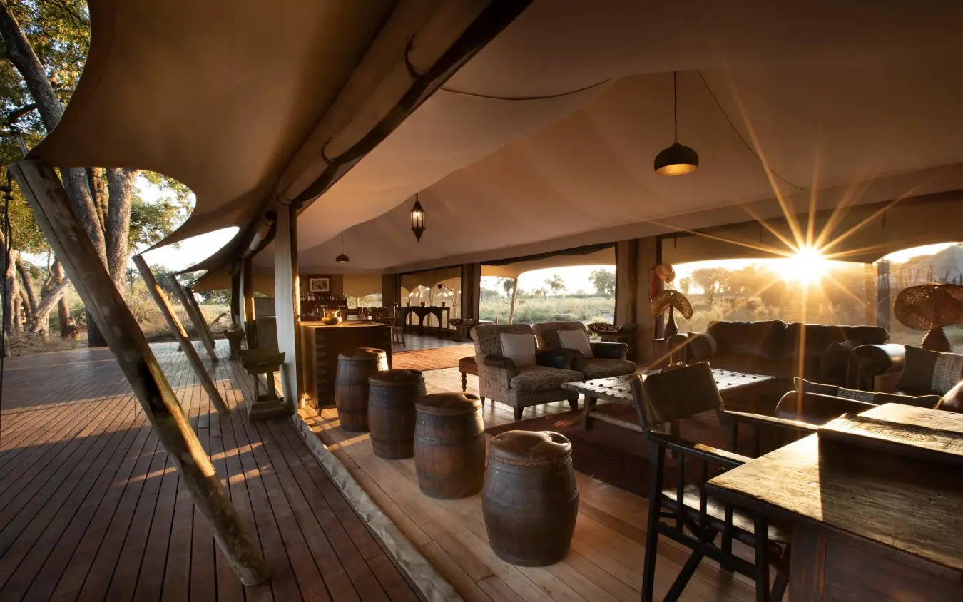 Open-air lounge with barrel seating and sunset views, Duba Explorers Camp, The Okavango Delta, Botswana