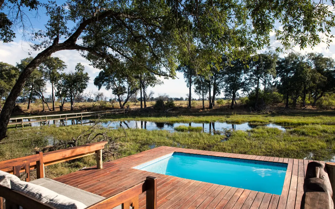 Pool deck overlooking wetland landscape with scattered trees, Duba Explorers Camp, The Okavango Delta, Botswana