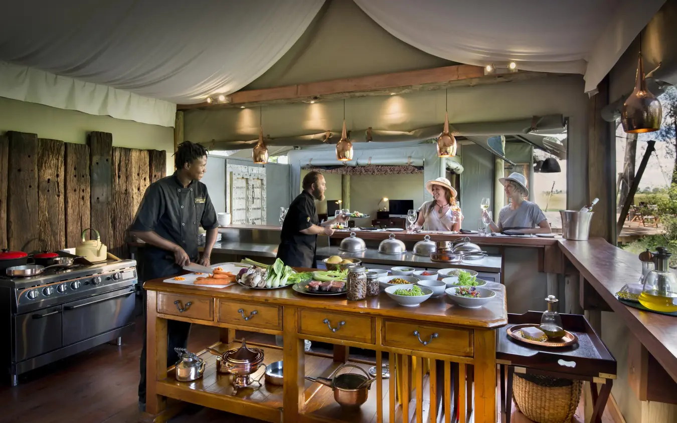 Open-air kitchen and dining area with chef preparing food, Duba Plains, The Okavango Delta, Botswana