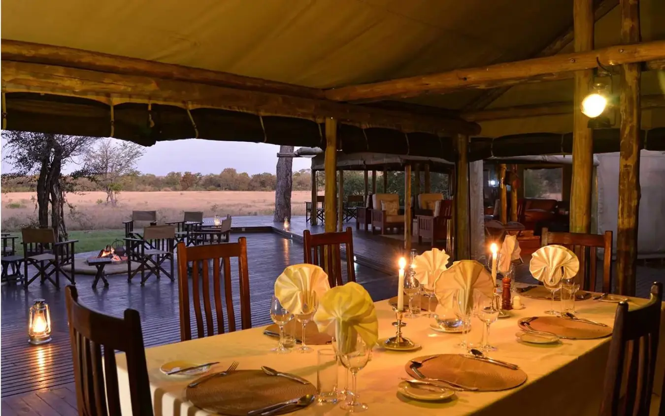 Dinner table set on covered deck at dusk overlooking savanna, Duba Plains, The Okavango Delta, Botswana