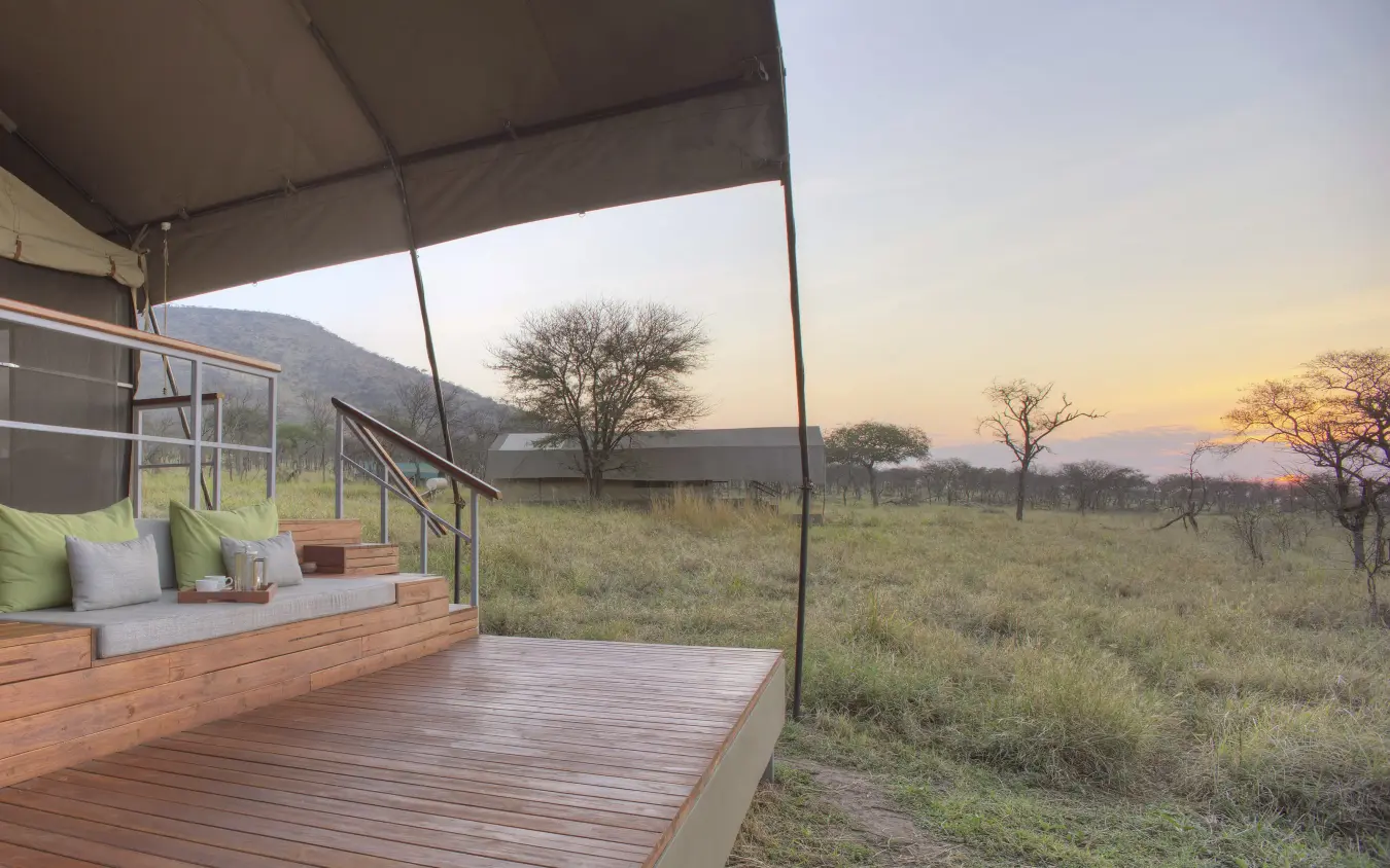 Wooden deck with cushioned seating overlooking savanna at sunset, Dunia Camp, Serengeti National Park, Tanzania