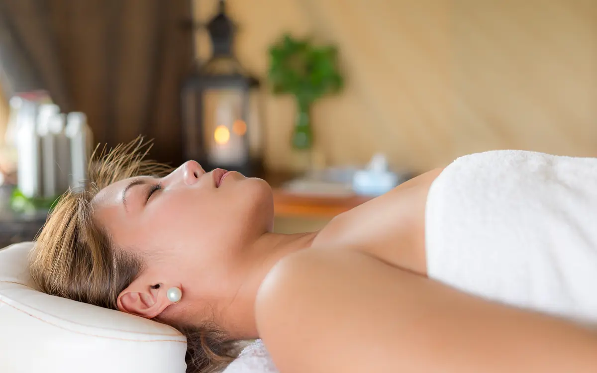 Woman relaxing on spa treatment bed in serene wellness room, Elephant Bedroom Camp, Samburu Reserve, Kenya