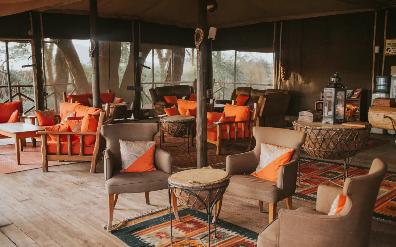 Safari lodge interior with orange cushions and panoramic windows overlooking bush landscape, Elephant Bedroom Camp, Samburu Reserve, Kenya