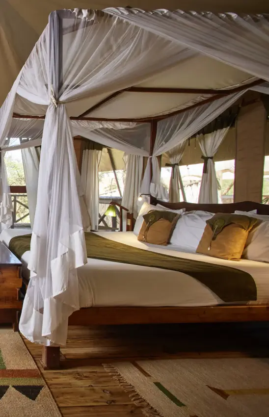 Four-poster bed with white drapes overlooking landscape through windows, Elephant Bedroom Camp, Samburu Reserve, Kenya