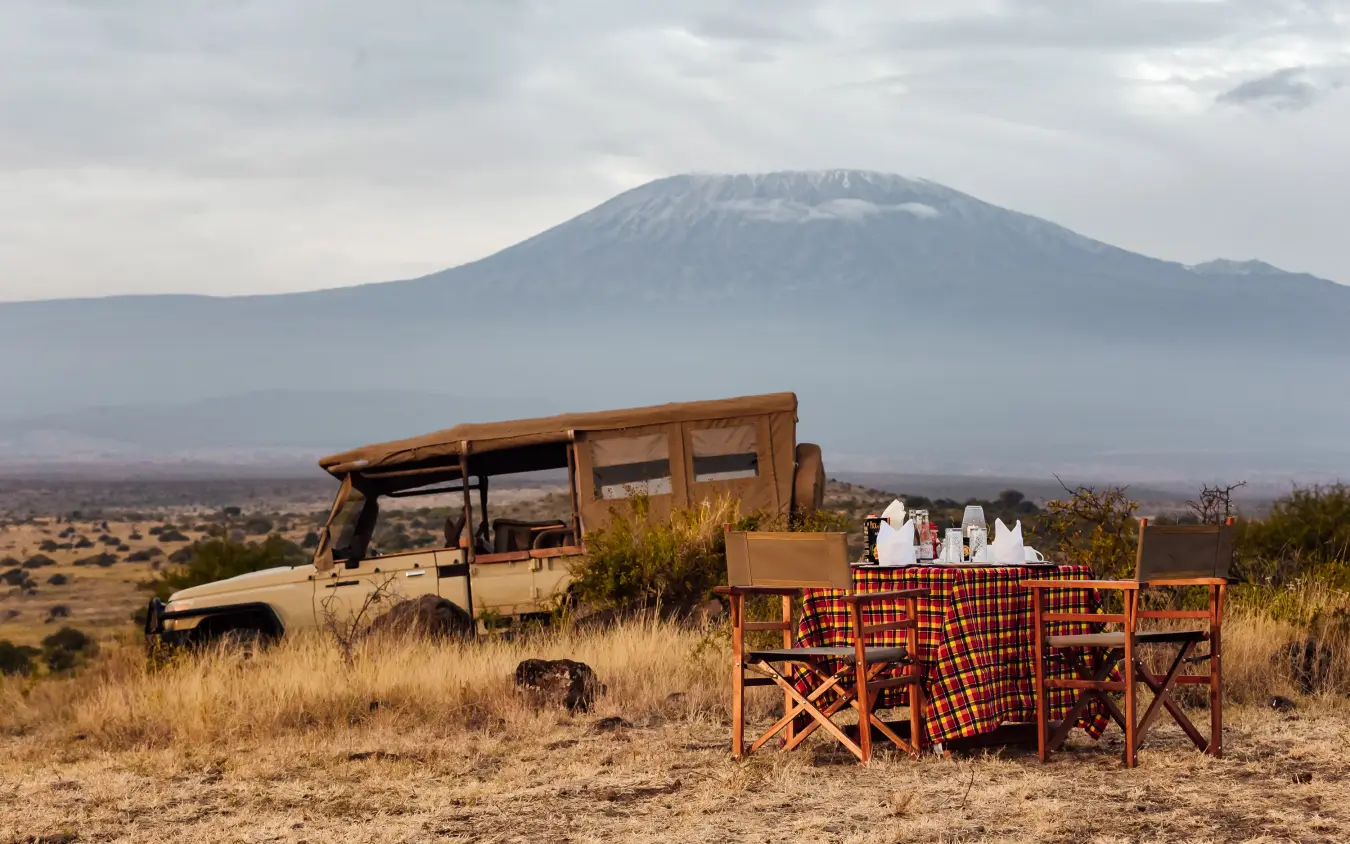 Safari vehicle with dining setup and snow-capped mountain in background, Elephant Gorge Camp, Amboseli and Chyulu Hills, Kenya
