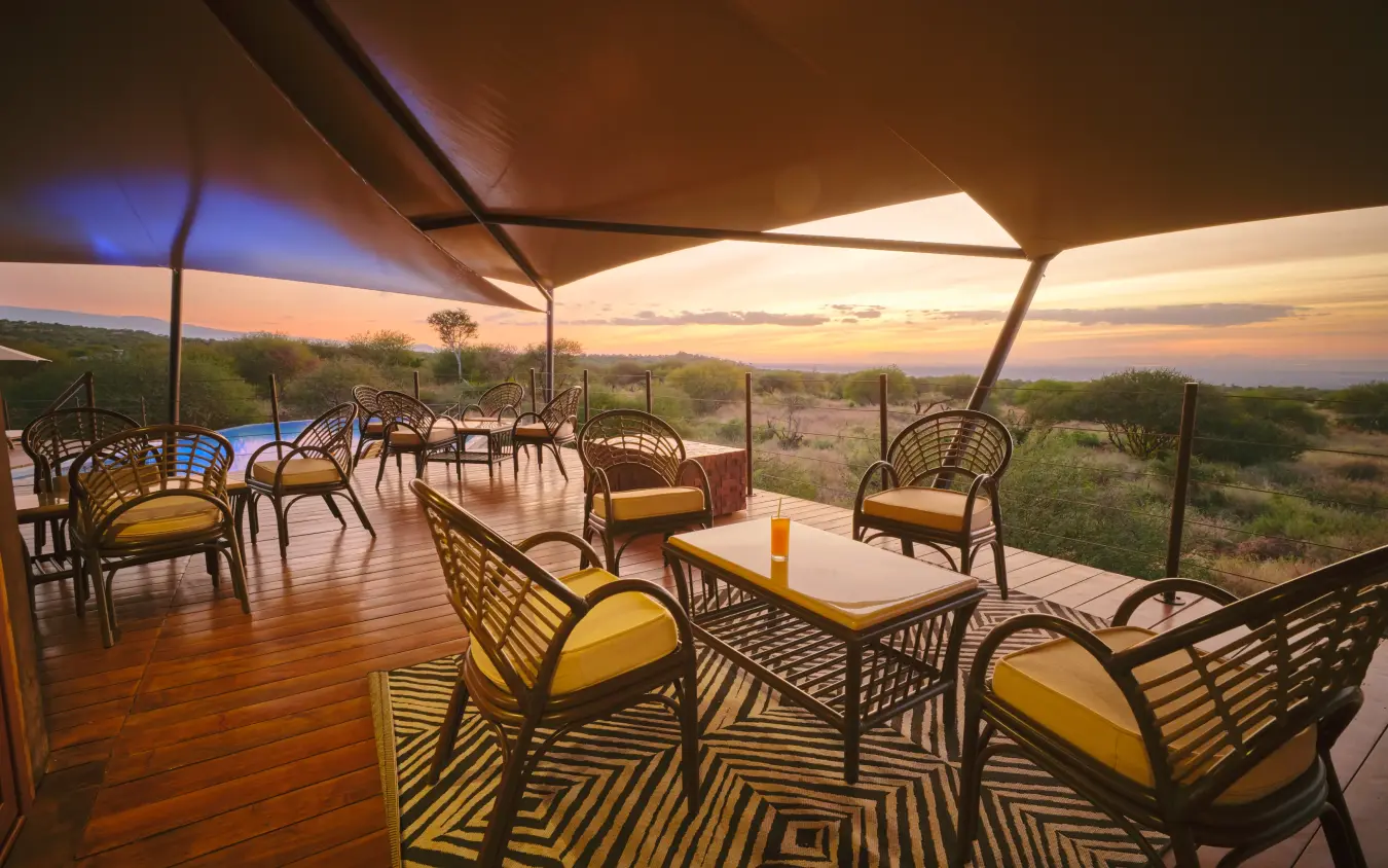 Covered deck with chairs overlooking savanna landscape at sunset, Elephant Gorge Camp, Amboseli and Chyulu Hills, Kenya