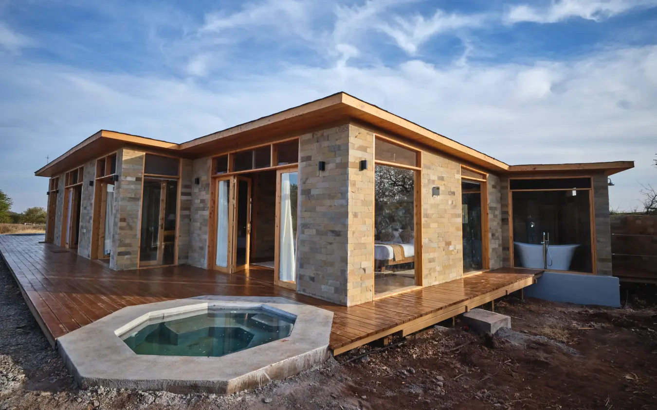 Modern stone lodge with wooden deck and outdoor hot tub overlooking plains, Elephant Gorge Camp, Amboseli and Chyulu Hills, Kenya