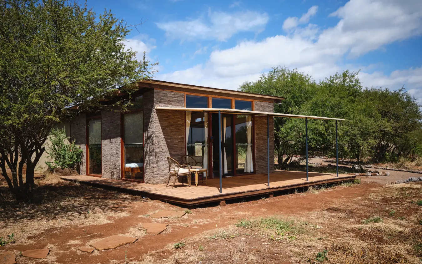 Modern brick lodge with wooden deck and metal railings in bushland setting, Elephant Gorge Camp, Amboseli and Chyulu Hills, Kenya