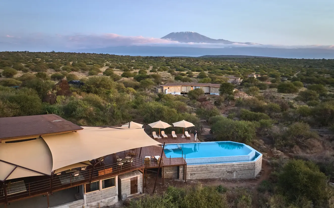 Luxury lodge with pool and mountain view across savanna landscape at dusk, Elephant Gorge Camp, Amboseli and Chyulu Hills, Kenya