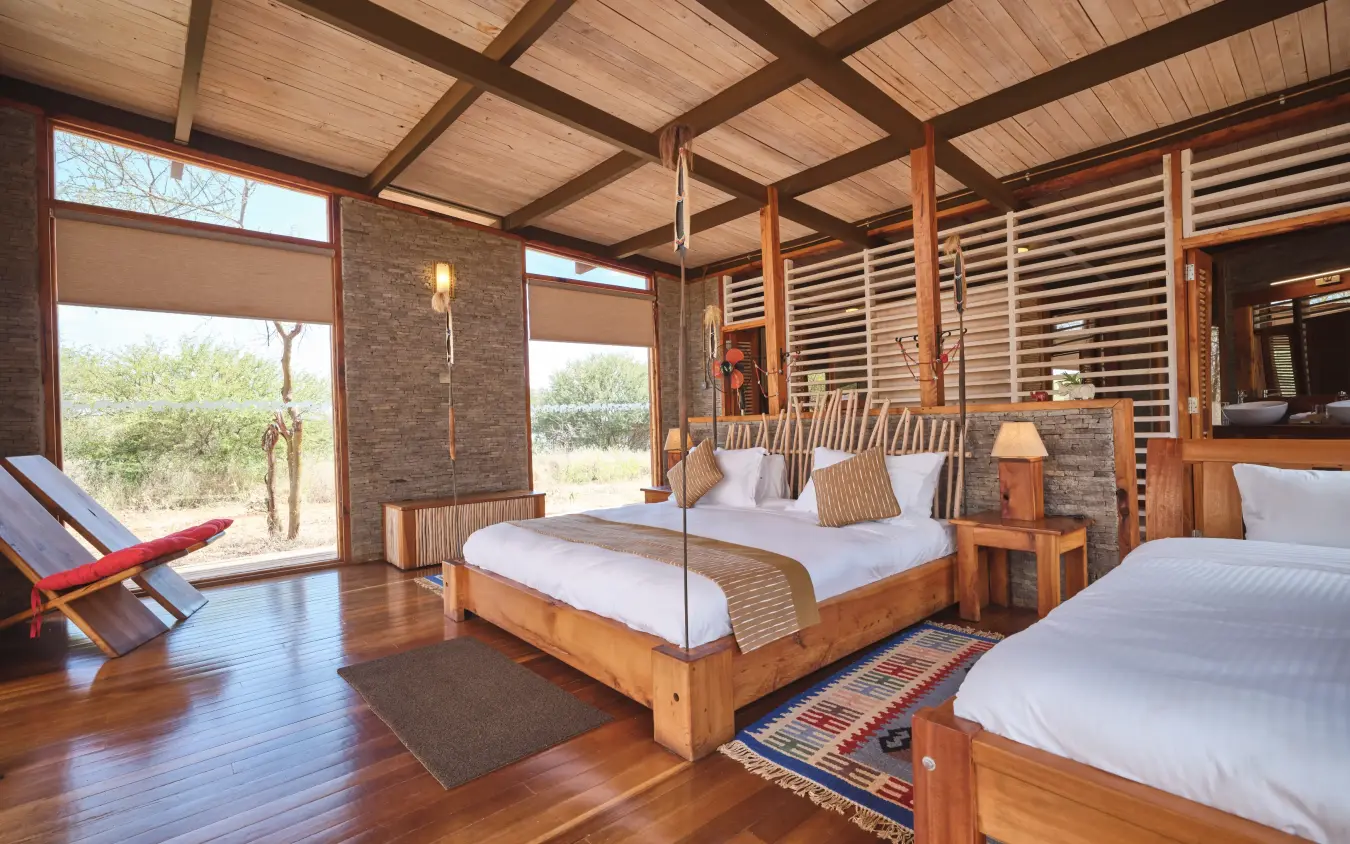 Luxury safari lodge bedroom with wooden beds and savanna views through large windows, Elephant Gorge Camp, Amboseli and Chyulu Hills, Kenya