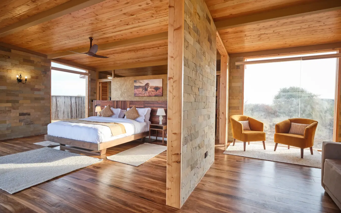 Spacious bedroom suite with wooden beams and panoramic windows overlooking bushland, Elephant Gorge Camp, Amboseli and Chyulu Hills, Kenya